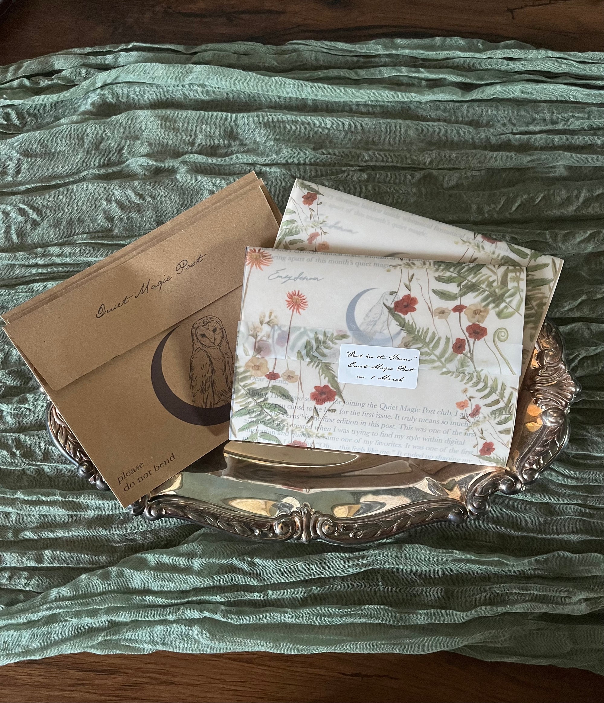 Decorative tray with floral cards and envelopes on a textured fabric background