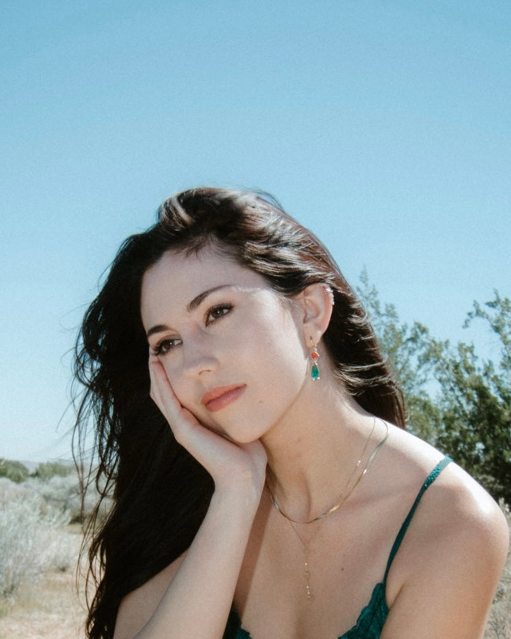 Woman with dark hair and green dress against a clear blue sky